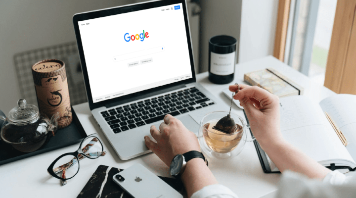Desk with computer and hands pouring coffee